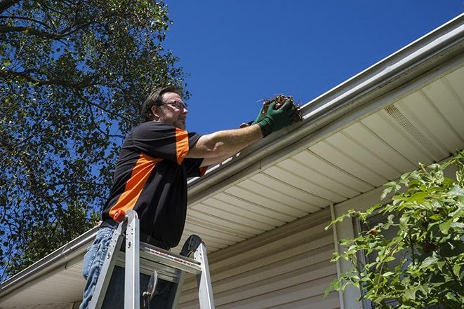 skilled laborer conducting repairs on a house's gutter in Ashaway